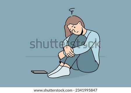 Sad woman is waiting for phone call, sitting on floor and suffering from loneliness or lack of friends. Sad girl sadly awaits arrival of sms message about replenishing bank account