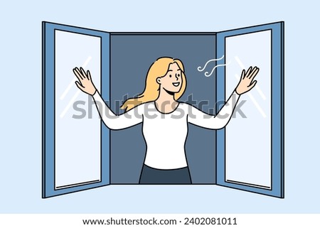 Woman opens window enjoying fresh air coming from street into apartment, and smilingly looks at passers-by. Girl stands near window and wants to check room to get rid of unpleasant smell in house.