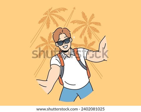 Man tourist in sunglasses takes selfie traveling to hot resort or sunny beach with palm trees. Young guy tourist with backpack smiles photographing himself for blog about vacation trip