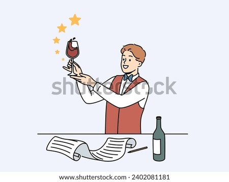 Man sommelier holds glass red wine and evaluates taste of noble alcoholic drink standing near table with bottle and sheet of paper. Guy studying at sommelier school wanting to get job in restaurant