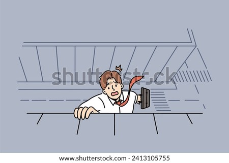 Businessman falls from roof building, trying to hold on and call for help, holding on to edge of bridge with hand. Metaphor bankruptcy and career crisis for businessman suffered due to wave of layoffs