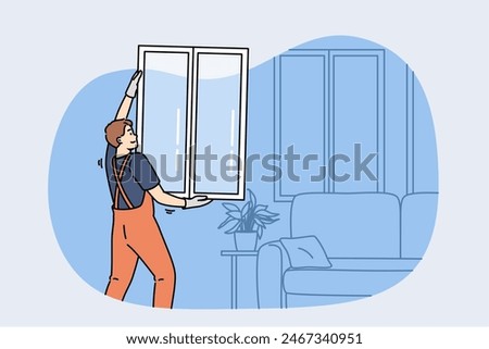 Man master changing windows in apartment, holding casement in hands standing near sofa. Replacing windows in home during renovations to improve energy efficiency and building exterior