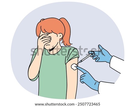 Crying little girl is afraid of injections and closes eyes during injection in shoulder and vaccination against measles or flu. Hands of doctor with syringe making injection to child