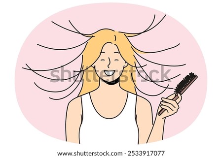 Woman combs hair and smiles, seeing effect of static magnetization of hairstyle. Funny young blonde girl takes care of own hair getting ready for date and laughing feeling surge of positive emotions