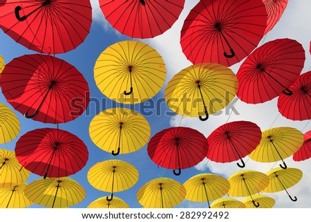 Collection of multi colored umbrellas hanging up in an open position over a street