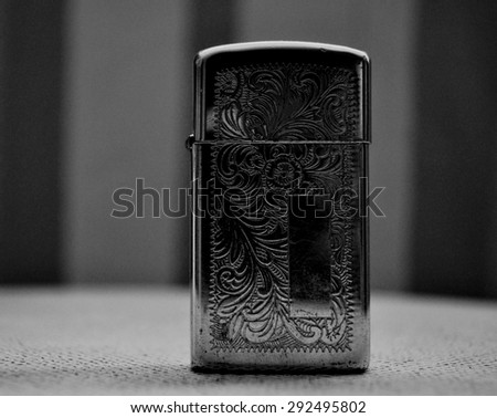 Beautiful old lighter,, placed on a white chair, inside a house, sunny day, a white curtain background, vintage photo, bokeh style .. the chair near a window, .., captured in black and white