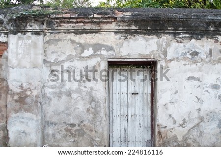 Old wooden door is locked on old plaster walls.