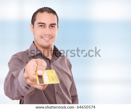 Young man giving his credit card looking at the camera,  blue background
