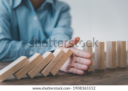 close-up hand The hand of a businessman who is stopping or preventing a falling block.Risk protection concept,Eliminating the risk