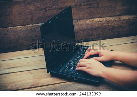 hands typing on laptop  on wooden background