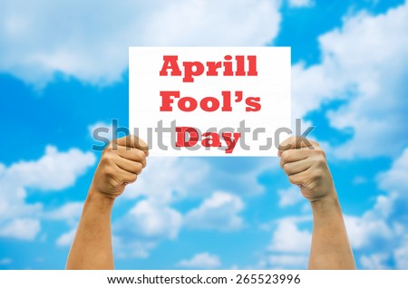 Hand holding April Fool\'s Day card on blue sky background