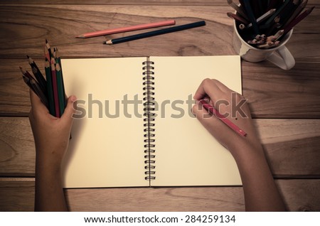 Hand-written note in pencil on a wooden table - hand focus