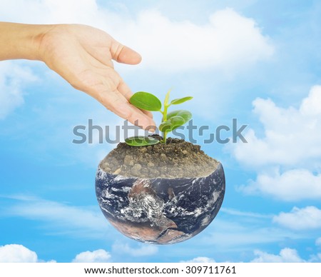 Hand watering a tree on a nature background  Elements of this image furnished by NASA