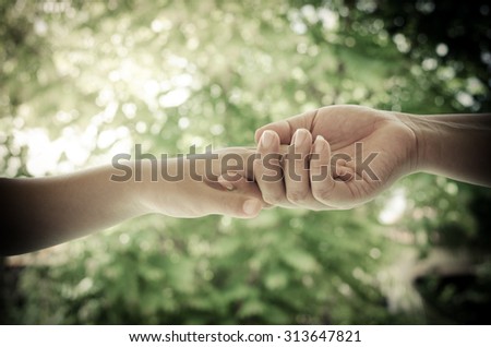 Hand Clasp on blurred abstract nature background