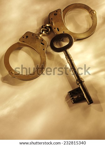 Old church key with police handcuffs on a gold background with copy space.