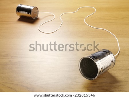 Two tin cans joined with a cord on a wooden background for primitive communication.