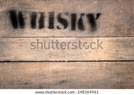 Wooden box bearing the word whiskey in spray black.