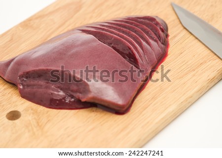 Fresh and raw pig\'s liver with stainless sharp knife on chopping block, ready for cooking