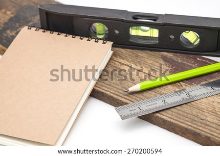 Spirit level with ruler, note book, wood and pencil for measuring with white background
