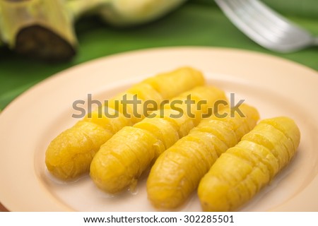 Fresh and delicious boiled bright yellow banana on metal plate with green leaf for sweet snack background