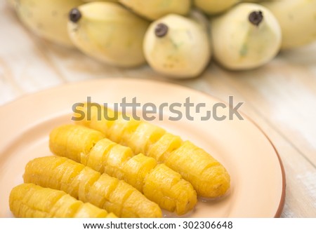 Fresh and delicious bright yellow banana on brown metal plate with coconut milk for local Thai sweet dessert background