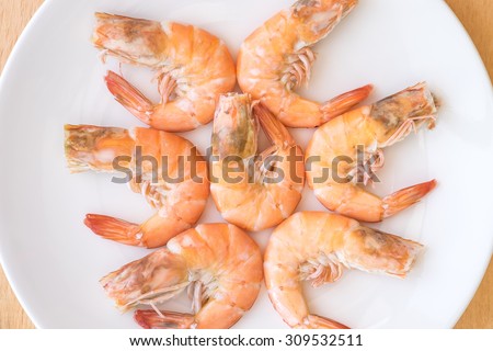 Fresh steamed or boiled jumbo shrimps or prawns on white ceramic plate on table