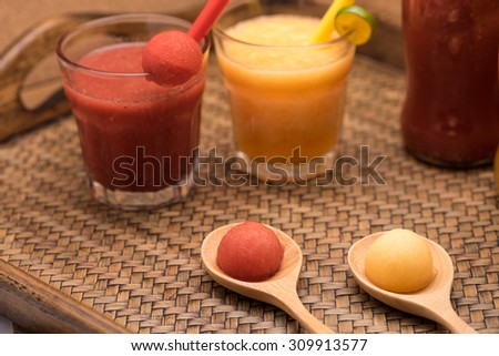 Fresh melon and cantaloupe fruit juices in glasses with carved fruit balls on wooden spoon