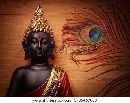 Buddha statue with wooden background and peacock feather/wallpaper image with peacock feather and smiling buddha/peaceful image of buddha meditating with wooden backdrop