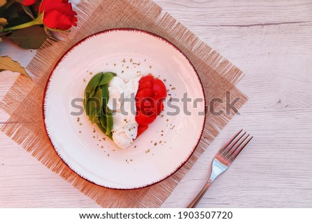 
Heart shaped Italian Caprese Salad arranged by Italian basil,buffalo mozzarella and tomatoes look like Italian Flag on plate with white wood table background.Love Italian food concept for Valentine