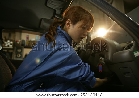 Side profile of a female auto mechanic examining a car