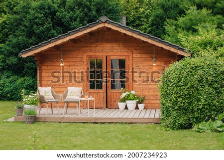 Modern garden chairs and flowers in front of a wooden hut. Garden joy in summer. Relax in the garden and enjoy the beautiful weather. Lavender and hydrangea in pot next to a garden shed 