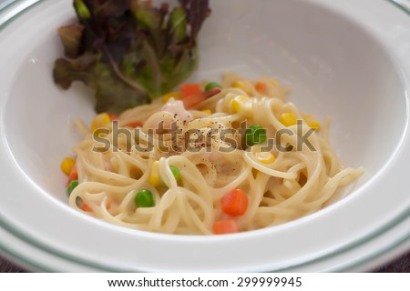 Dish of spaghetti carbonara with carrots, corn, peas, shrimp.