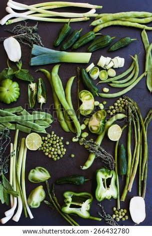 Collection of fresh green vegetables on blue metal table, asparagus, leek, string beans, french beans, fresh peas, lettuce, tomatoes, peppers, onions, radicchio. Organic and healthy vegetables.