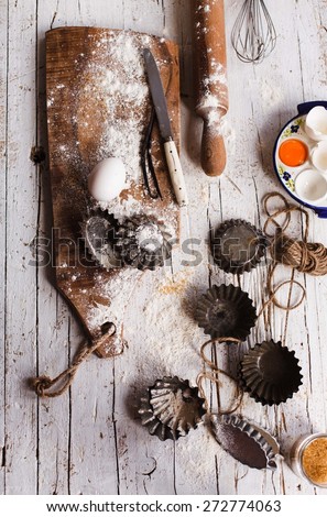 Baking and pastries retro image. Various vintage kitchen utensils, props and ingredients  on a rustic wooden table with flour. Top view.