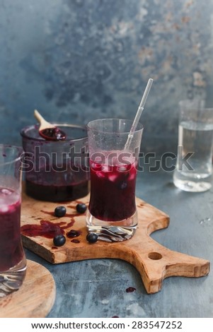 Preparing fresh blueberry summer drink in glasses over and vintage cutting board. Rustic dark table. Healthy drink concept.