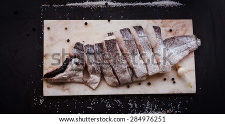 Clean and cut fish fillets served on marble cutting board with spices over on dark background. banner concept .