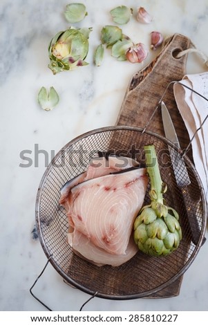 Tuna steaks with artichoke for dinner party. healthy, diet and cooking concept.  Rustic image from above .