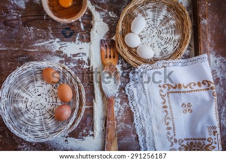 Rustic still life of baking flour with vintage sieve and kitchen towel on distressed wood.
