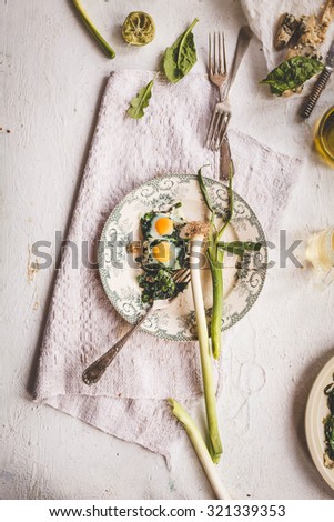 Ideal idea fro breakfast meal. A plate of fried Quail eggs and spinach veggies with leeks over on a vintage linen napkin.  Rustic style.