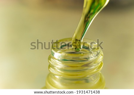 Yellow oil drips into a glass bottle from a pipette. Cosmetic oil. A drop of hemp oil. Dropper with oil close-up.