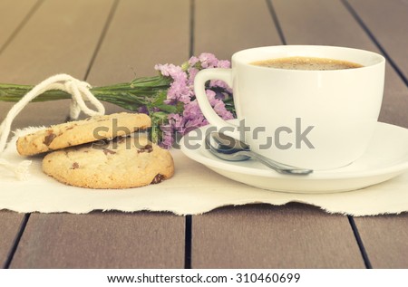 Coffee and purple flower witn bean and white glass, dish, cloth on brown wooden