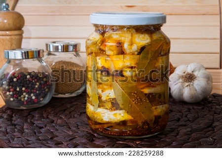 Homemade spicy marinated cheese with oil, onion, garlic and spicy spices, wooden background
