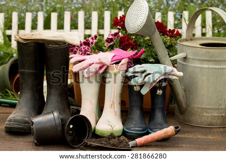 gardening tools, adult and child boots and handshoes in the garden
