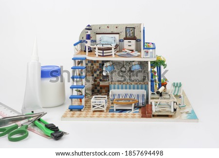 Miniature Dollhouse - beachfront house in small scale in white background with glue and equipment to build - Hobby and leisure time Сток-фото © 