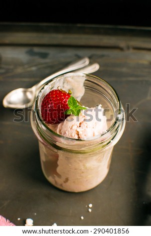 Strawberry ice cream in a jar on dark background
