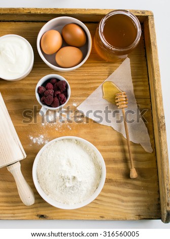 Ingredients for a cake with raspberries on a wooden pastry board
