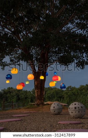 outdoor furniture in garden  concrete bench in sphere shape and colorful hanging lamp under tree