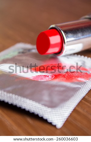 condom with the imprint of red lipstick on her lips