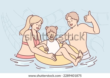 Happy family posing swimming in hotel pool during summer vacation or traveling to tropical island. Teenage girl with parents swim in pool posing for photo in memory of tourist trip 