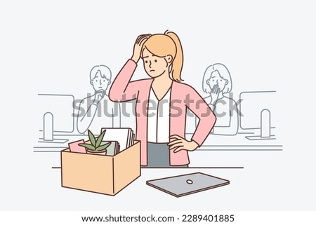 Upset woman standing near table with box after dismissal of manager or secretary position. Sad girl is preparing to leave workplace due to dismissal related to financial crisis or closure of company